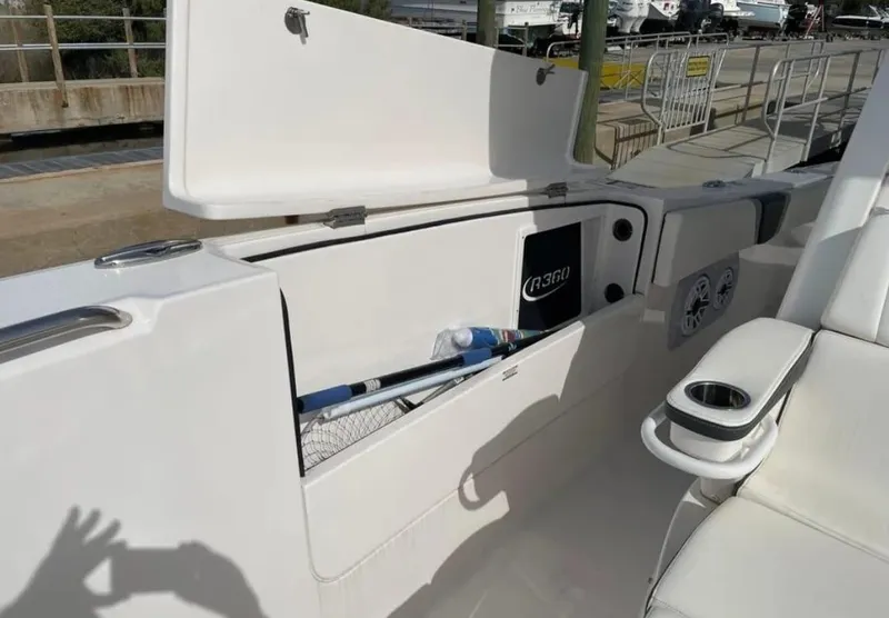 Slide: The Image of 2023 Robalo R360 Center Console boat storage compartment with open lid and fishing gear. - 15