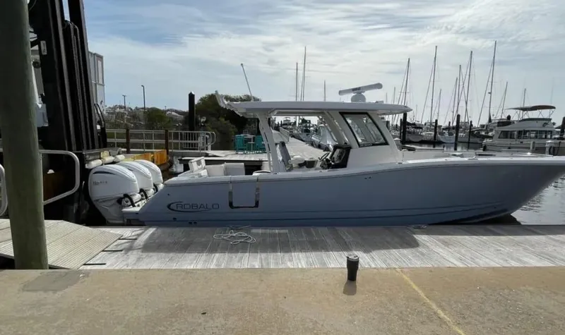 Slide: The Image of 2023 Robalo R360 Center Console boat docked at marina with twin engines. - 8
