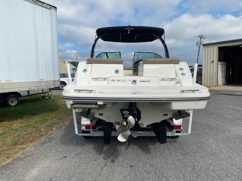 Slide: The Image of 2013 Sea Ray 270 SLX boat on trailer, parked outdoors near a warehouse. - 2