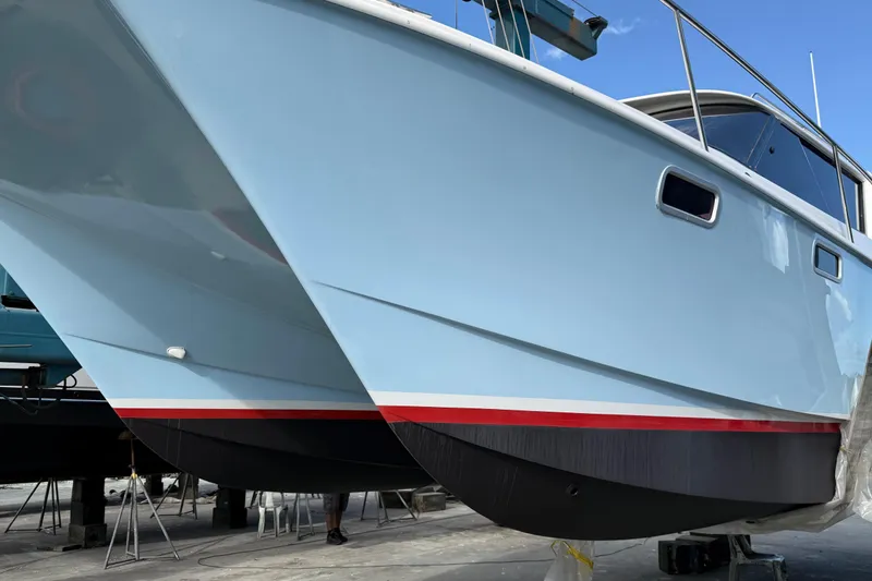 Slide: The Image of 2004 Roger Hill 9.5M boat on dry dock, showcasing sleek blue hull design. - 12