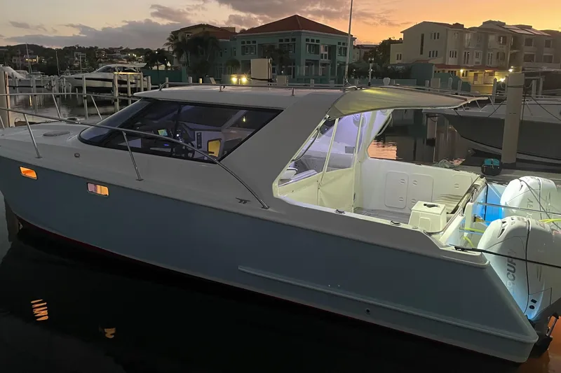 Slide: The Image of 2004 Roger Hill 9.5M boat docked at sunset, illuminated interior, calm marina setting. - 13