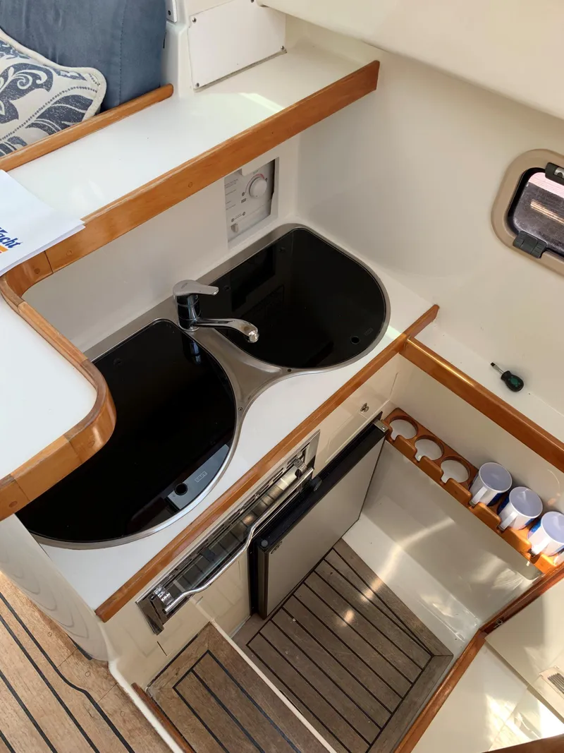 Slide: The Image of Compact kitchen area in a 2004 Roger Hill 9.5M boat with dual sinks and wooden accents. - 4