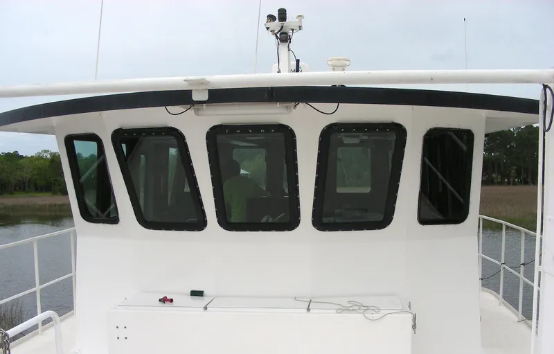 Slide: The Image of Custom 2000 Expedition boat docked by a serene riverside with lush greenery. - 5