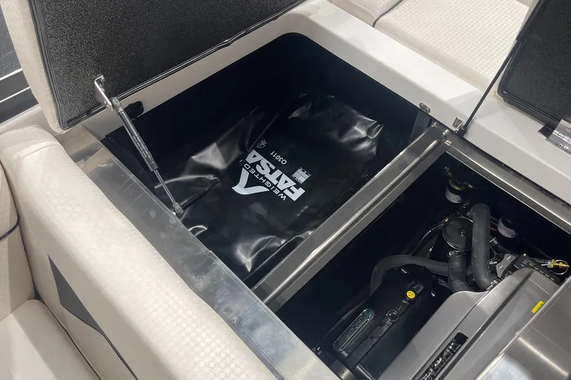 Slide: The Image of 2024 Supreme S220 boat storage compartment with ballast bag and engine components. - 23