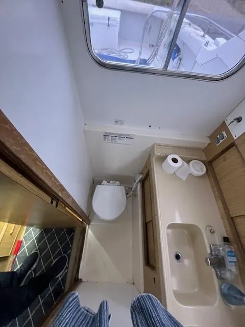 Slide: The Image of 1982 Bertram 28 Flybridge boat bathroom with sink, toilet, and window view. - 10