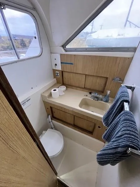 Slide: The Image of 1982 Bertram 28 Flybridge boat bathroom with sink, toilet, and towel rack. - 8
