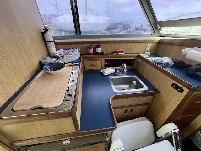 Slide: The Image of 1982 Bertram 28 Flybridge boat kitchen with sink, stove, and wooden cabinetry. - 9