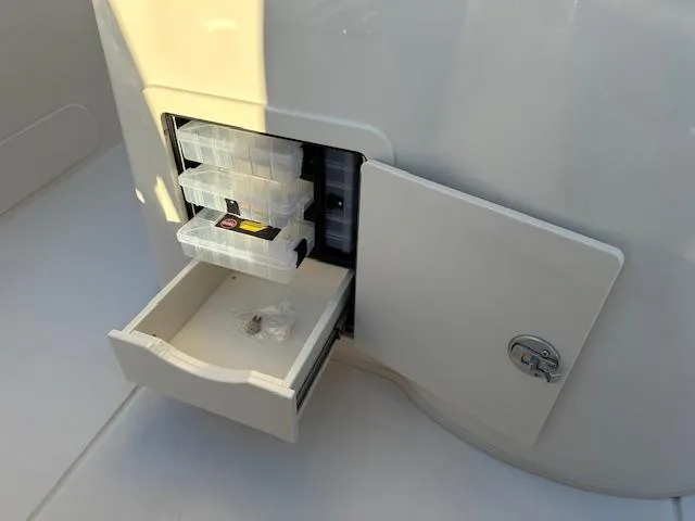 Slide: The Image of 2025 Grady-White 231 Coastal Explorer storage compartment with organized tackle boxes. - 19