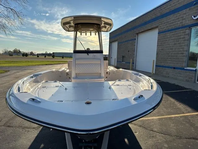 Slide: The Image of 2025 Grady-White 231 Coastal Explorer boat, docked near a warehouse, under clear skies. - 2