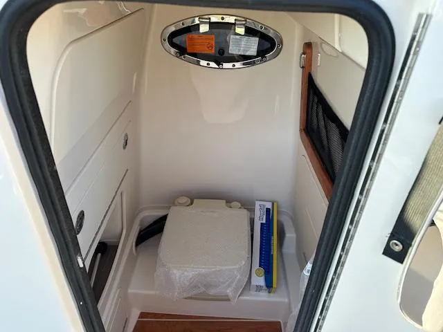 Slide: The Image of 2025 Grady-White 231 Coastal Explorer boat interior with compact toilet and storage. - 31