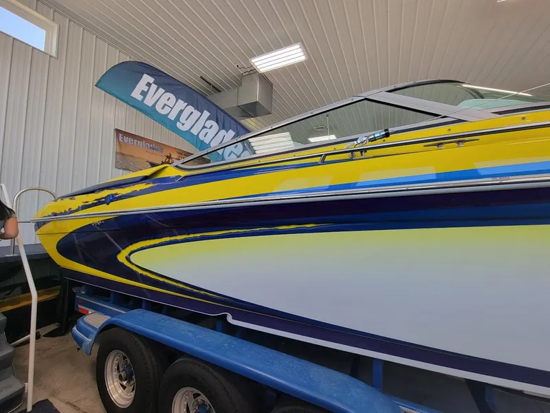 Slide: The Image of 1998 Formula 353 FASTech boat with vibrant yellow and blue design on trailer. - 5