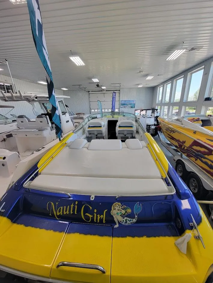 Slide: The Image of 1998 Formula 353 FASTech boat, "Nauti Girl," in showroom with vibrant yellow and blue design. - 6