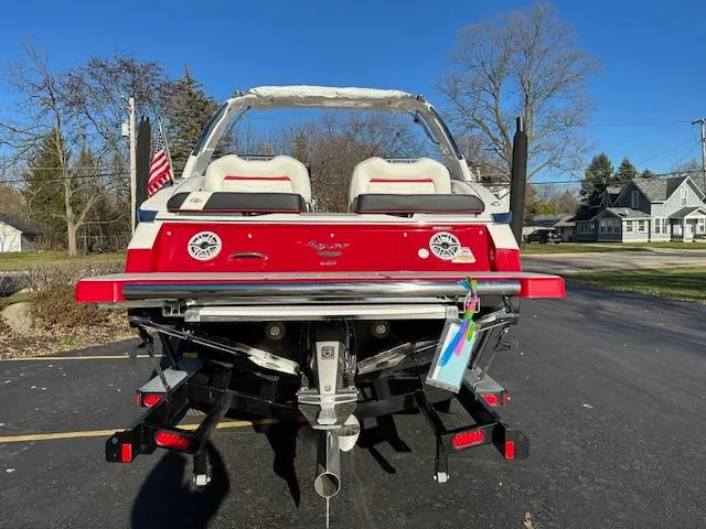 Slide: The Image of 2025 Regal LS9 Surf boat, rear view, parked on driveway with clear blue sky. - 3
