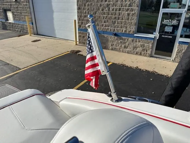Slide: The Image of 2025 Regal LS9 Surf boat with American flag on deck, parked near a building. - 32