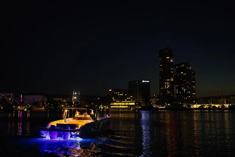 Slide: The Image of Wiszniewski Yachts W43, 2025 model, illuminated on water at night with city skyline. - 4