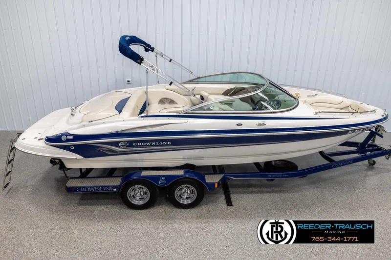 Slide: The Image of 2006 Crownline 230 LS boat on trailer in showroom, blue and white design. - 1