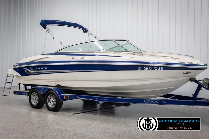 Slide: The Image of 2006 Crownline 230 LS boat on trailer in showroom, blue and white design. - 2