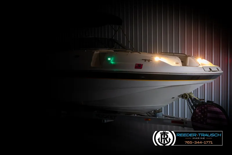 Slide: The Image of Chaparral 243 Sunesta 2002 boat with lights on, displayed in a dimly lit showroom. - 4