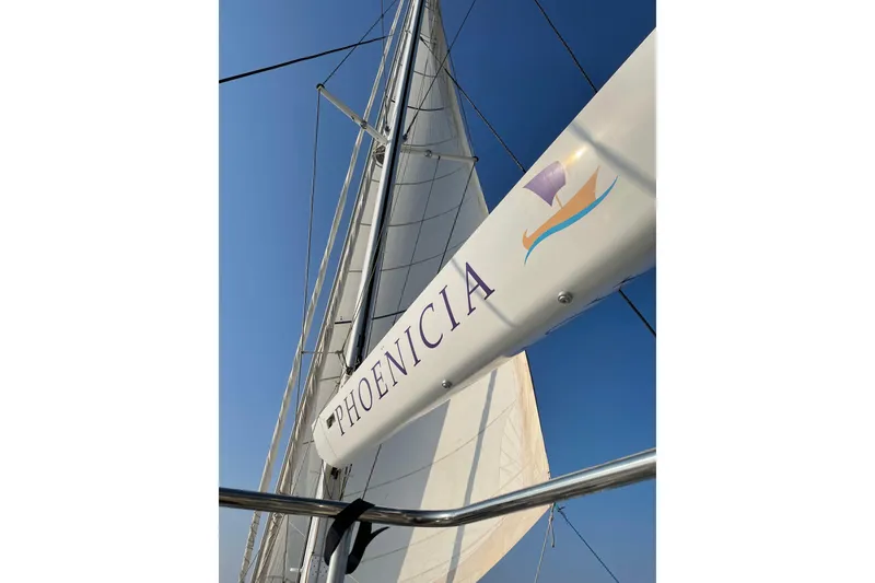Slide: The Image of Sail of Lagoon 620 yacht, 2014 model, with "PHOENICIA" branding against clear sky. - 61