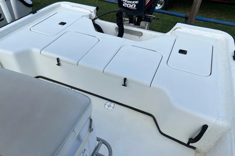 Slide: The Image of 2000 Triton 23 Tunnel boat interior with storage compartments and seating. - 13