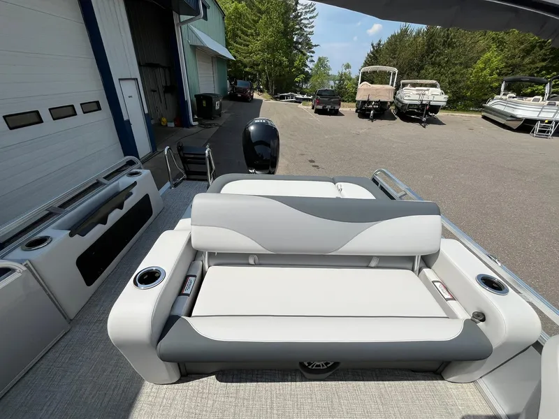 Slide: The Image of 2025 Avalon LSZ Versatile Rear Bench boat with sleek seating, parked outdoors. - 16