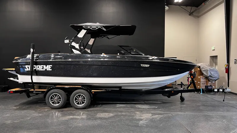 Slide: The Image of 2024 Supreme S220 boat on trailer in showroom, black and white design. - 1