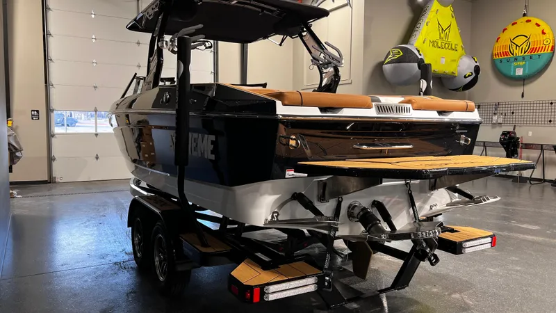 Slide: The Image of 2024 Supreme S220 boat in showroom, rear view with trailer and wakeboard racks. - 10