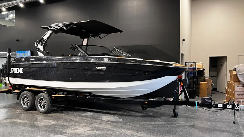 Slide: The Image of 2024 Supreme S220 boat on trailer in showroom setting. - 2