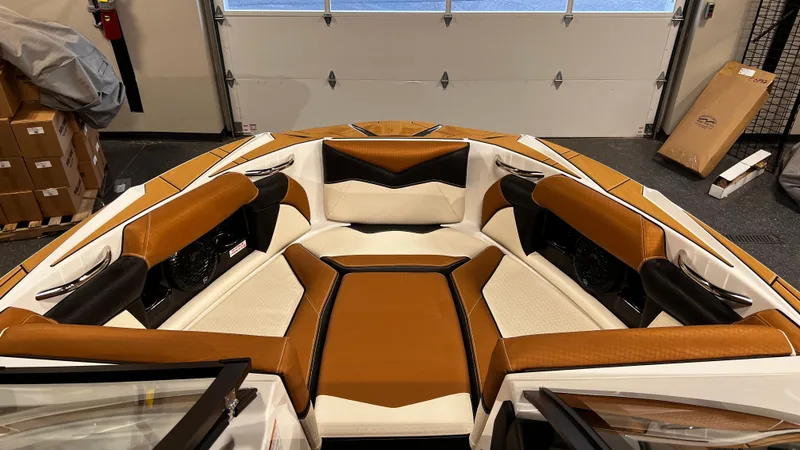 Slide: The Image of 2024 Supreme S220 boat interior with brown and white seating in a garage. - 30