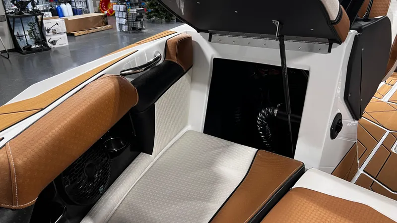 Slide: The Image of 2024 Supreme S220 boat interior with brown and white seating, open storage compartment. - 33
