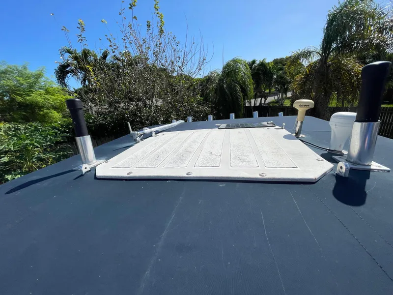 Slide: The Image of Grady-White X-26 Tiger Cat 1999 boat deck with rod holders, surrounded by lush greenery. - 47