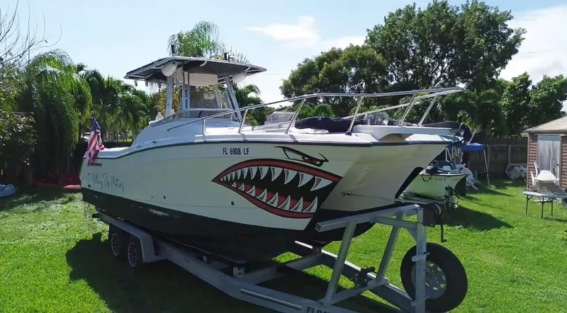 Slide: The Image of 1999 Grady-White X-26 Tiger Cat boat with shark mouth design on trailer, parked on grass. - 6