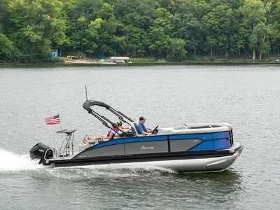 Slide: The Image of 2025 Barletta C22UC pontoon boat cruising on a lake with passengers. - 1