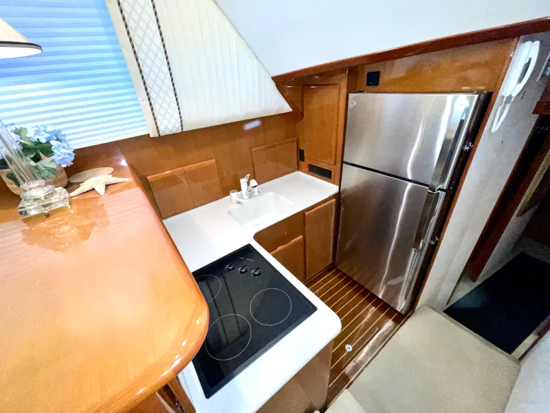 Slide: The Image of Compact kitchen in a 2001 Post 50 Convertible yacht with modern appliances and wooden cabinetry. - 18