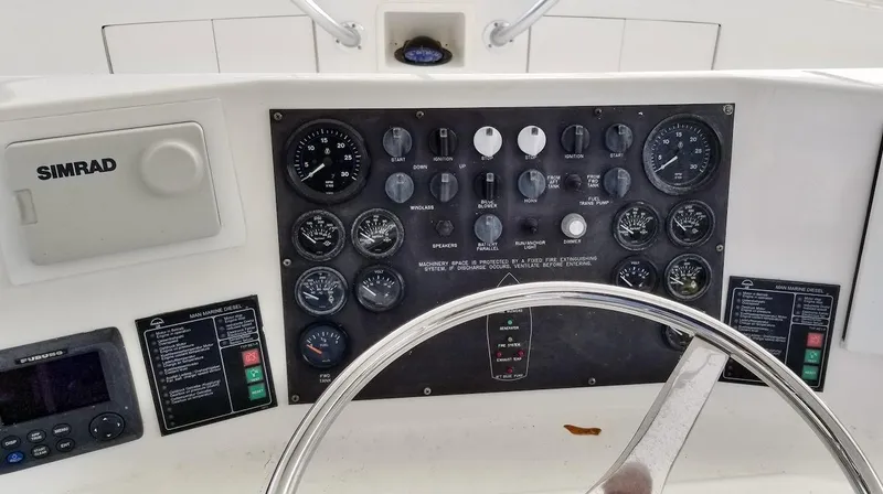Slide: The Image of Boat dashboard with steering wheel and control panel, featuring gauges and Simrad equipment, Post 50 Convertible. - 34