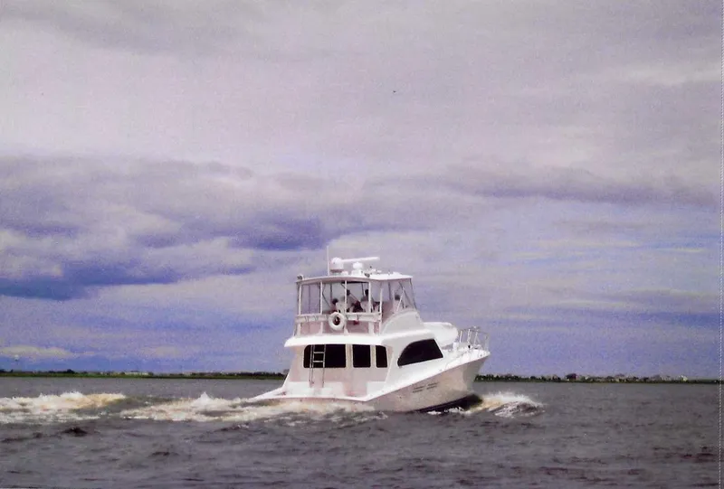 Slide: The Image of White 2001 Post 50 Convertible yacht cruising on open water under cloudy skies. - 39