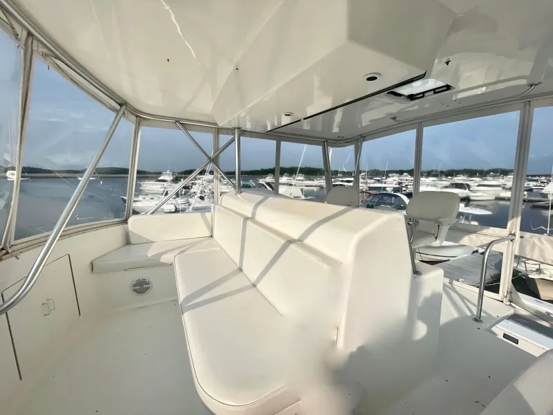 Slide: The Image of Interior view of a 2001 Post 50 Convertible yacht with white seating and marina background. - 45