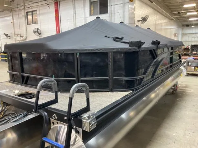 Slide: The Image of 2025 Bennington 23 SL pontoon boat with black canopy in a warehouse setting. - 15