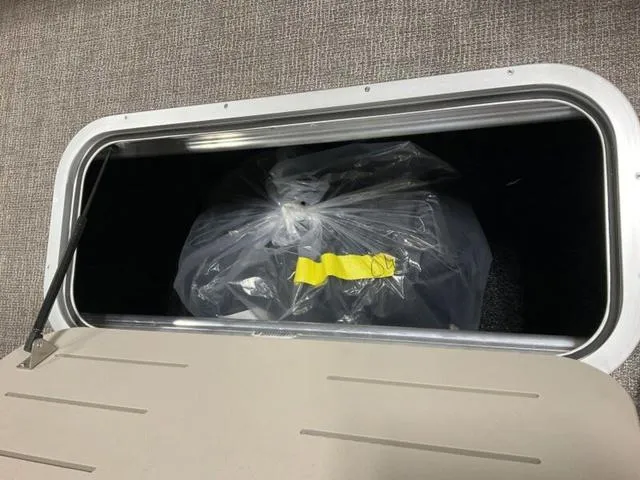 Slide: The Image of Storage compartment in 2025 Bennington 23 SL boat with a plastic-wrapped item inside. - 7