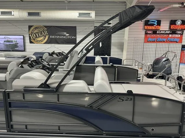 Slide: The Image of 2025 Bennington 23 SSB pontoon boat in showroom, featuring sleek design and modern seating. - 27