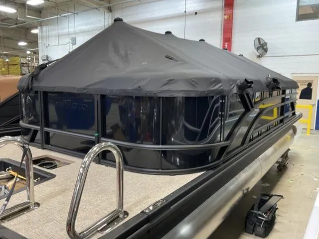 Slide: The Image of 2025 Bennington 22 SSR pontoon boat with black canopy in a warehouse setting. - 12