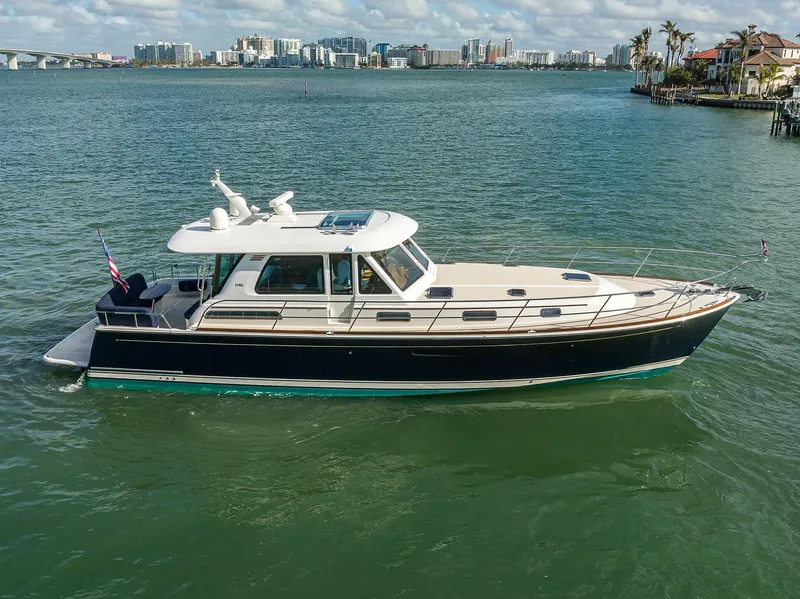 Slide: The Image of 2023 Sabre 48 Salon Express yacht on calm waters, cityscape in background. - 14