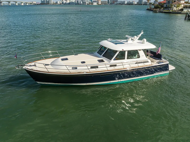 Slide: The Image of 2023 Sabre 48 Salon Express yacht on calm water, cityscape in background. - 19