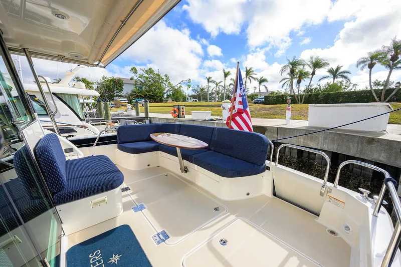 Slide: The Image of 2023 Sabre 48 Salon Express yacht deck with seating and table, docked under a blue sky. - 39