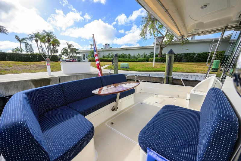 Slide: The Image of 2023 Sabre 48 Salon Express yacht with blue seating and wooden table, docked under a sunny sky. - 40