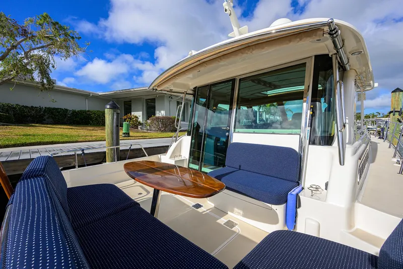 Slide: The Image of 2023 Sabre 48 Salon Express yacht with outdoor seating and table, docked under blue skies. - 42