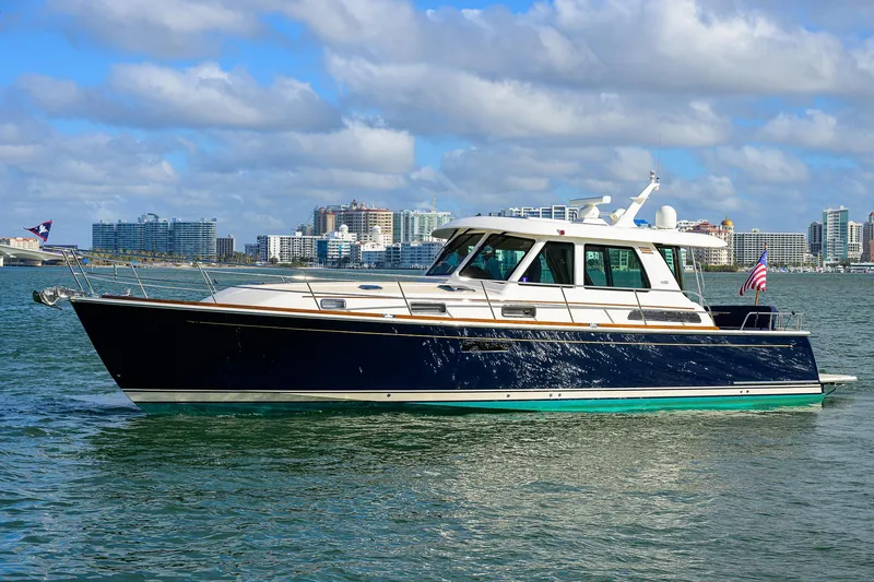 Slide: The Image of 2023 Sabre 48 Salon Express yacht cruising on a sunny day with city skyline backdrop. - 6