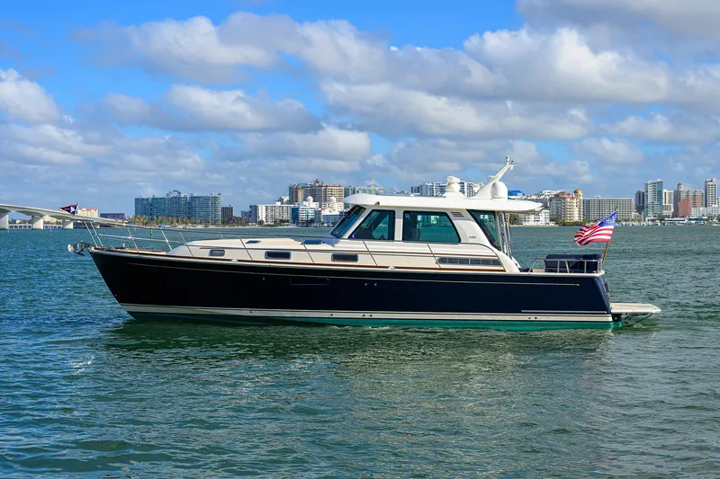 Slide: The Image of 2023 Sabre 48 Salon Express yacht cruising on a sunny day with city skyline backdrop. - 8