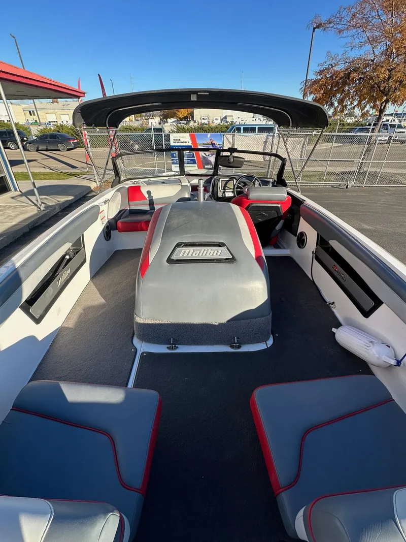 Slide: The Image of 2019 Malibu TXi Mo boat interior with seating and steering wheel, parked outdoors. - 10