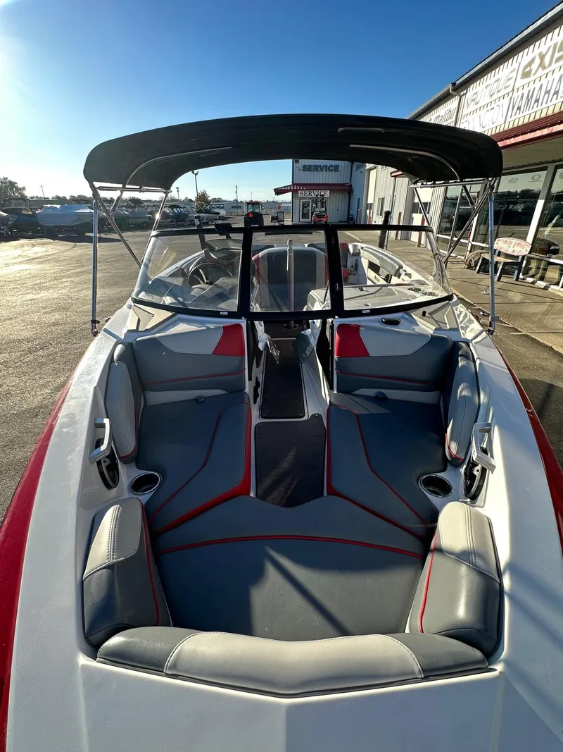 Slide: The Image of 2019 Malibu TXi Mo boat with spacious seating and canopy, parked outdoors. - 11